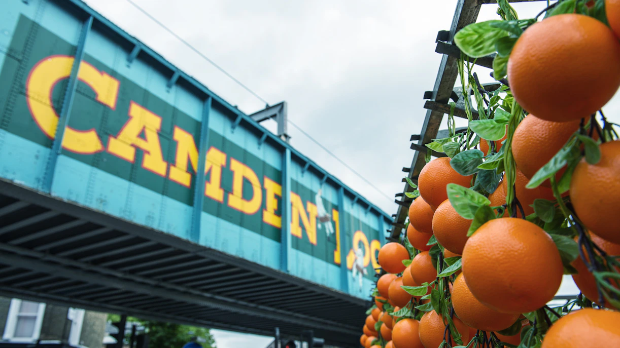 Oranges displayed at KERB Camden Market with Camden Lock bridge in London.