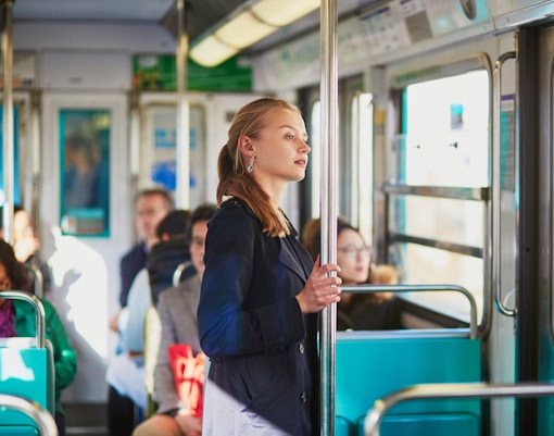 Person standing inside a Paris metro train holding a pole.