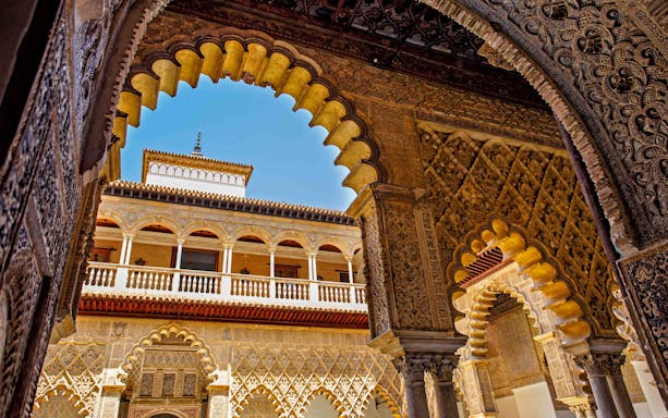 Alcazar of Seville intricate arches and detailed Moorish architecture.