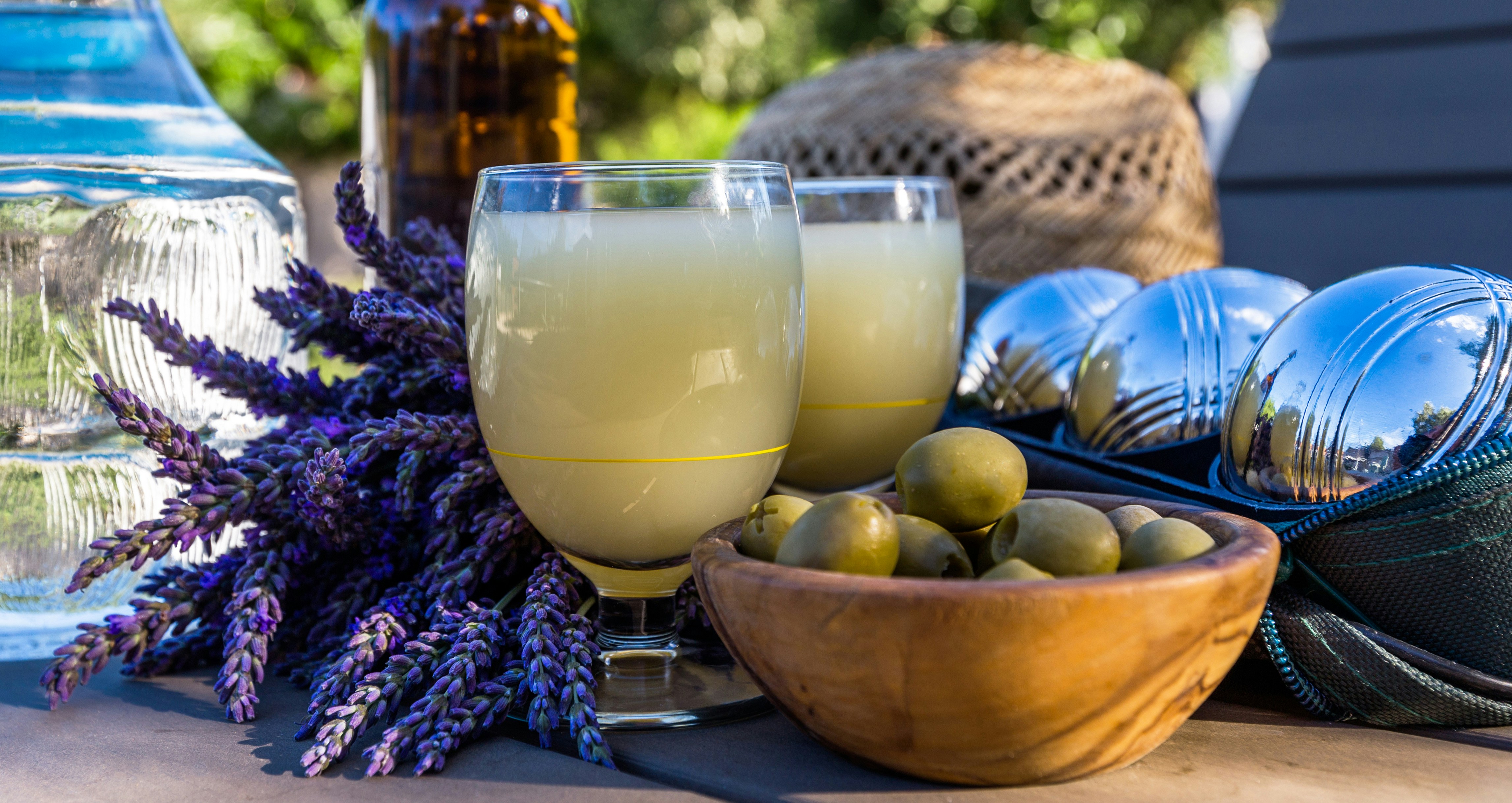 Glass of Ricard drink with ice and lemon slice on a table in a French café setting.