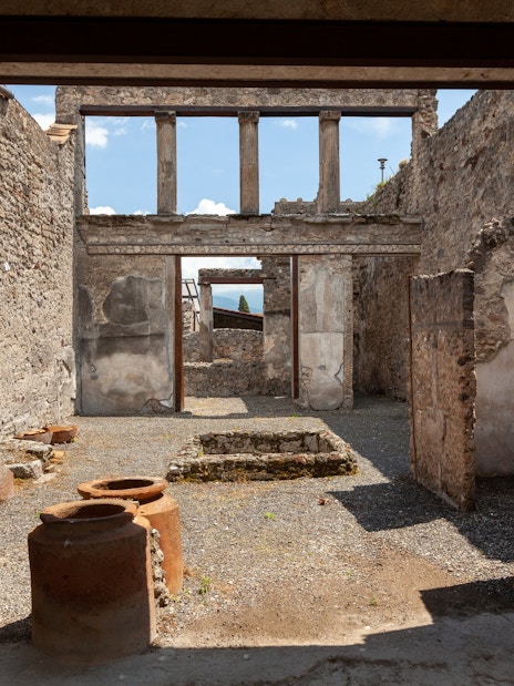 Pompeii ruins with ancient stone walls and pottery, viewed by tourists on a Rome day trip.