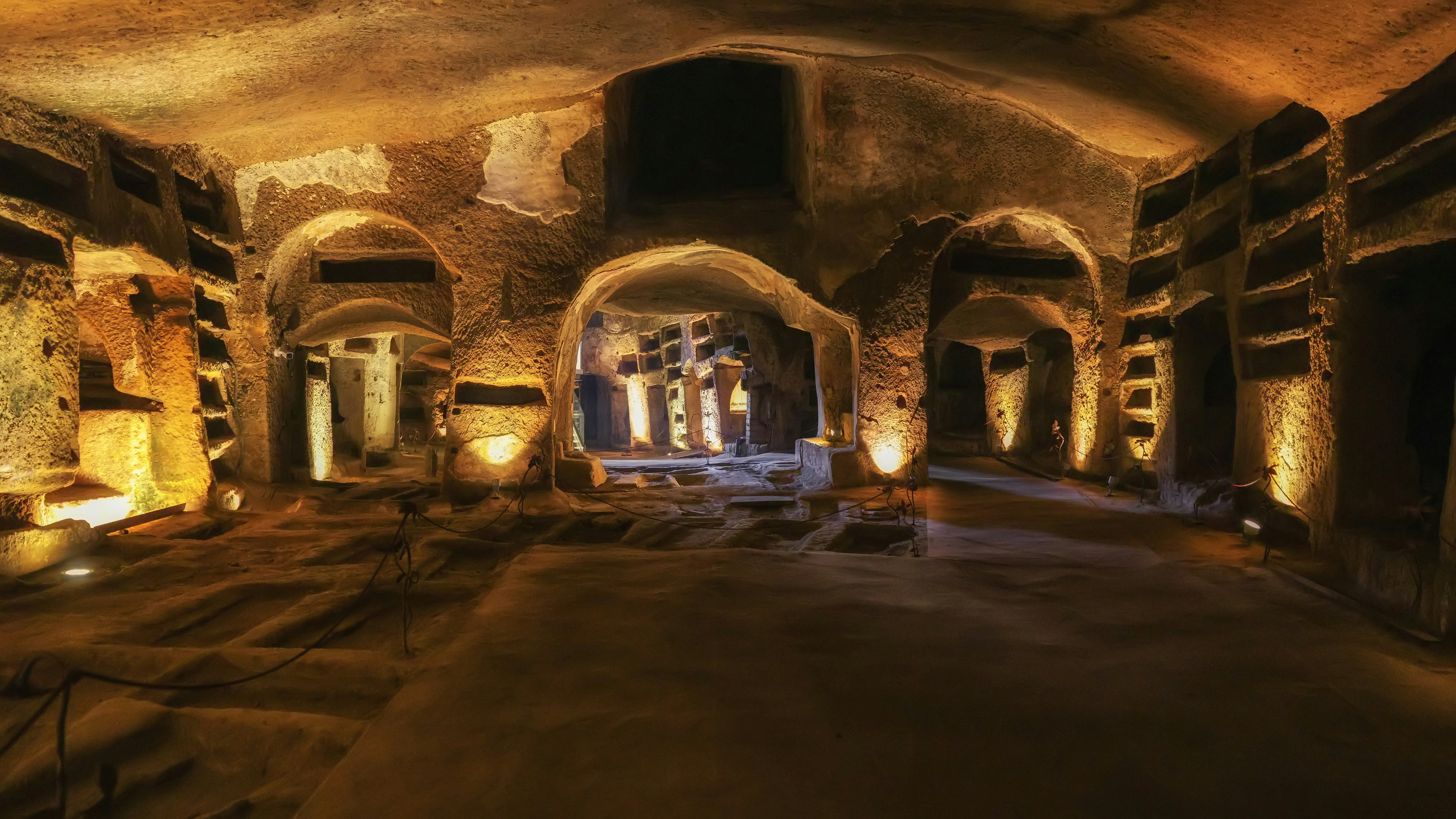 Naples Underground tunnels with illuminated ancient arches and stone walls.