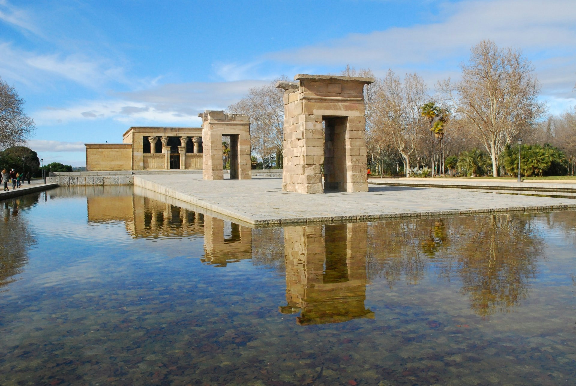 Temple of Debod in Madrid with reflection in water and surrounding trees.