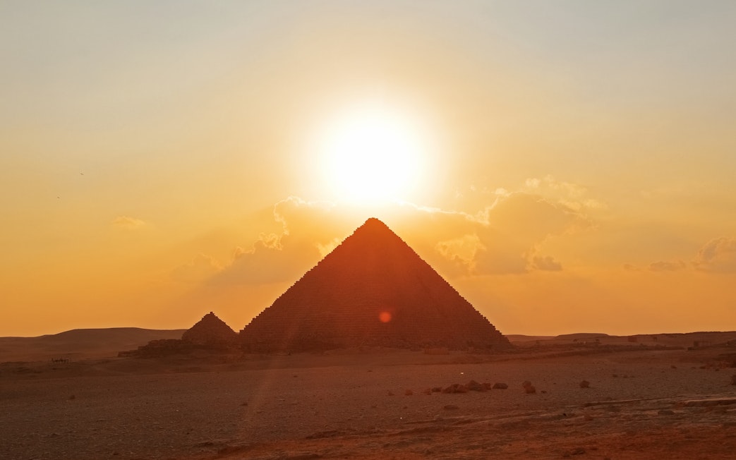 Pyramids of Giza with sunset behind Khufu Pyramid, Egypt.