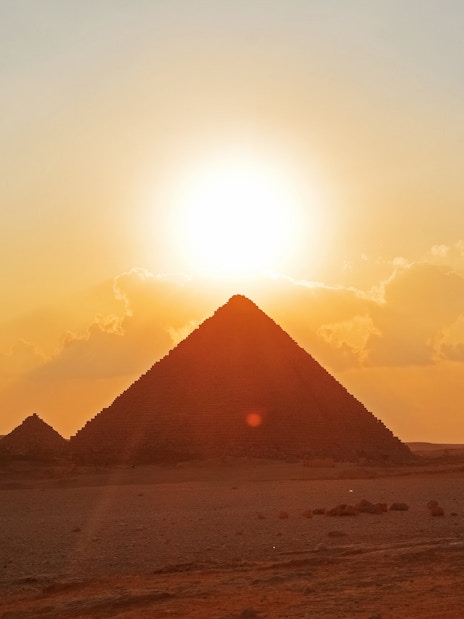 Pyramids of Giza with sunset behind Khufu Pyramid, Egypt.