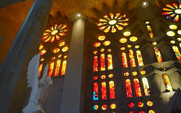 Stained glass windows inside Sagrada Familia, Barcelona, showcasing vibrant red and yellow patterns.