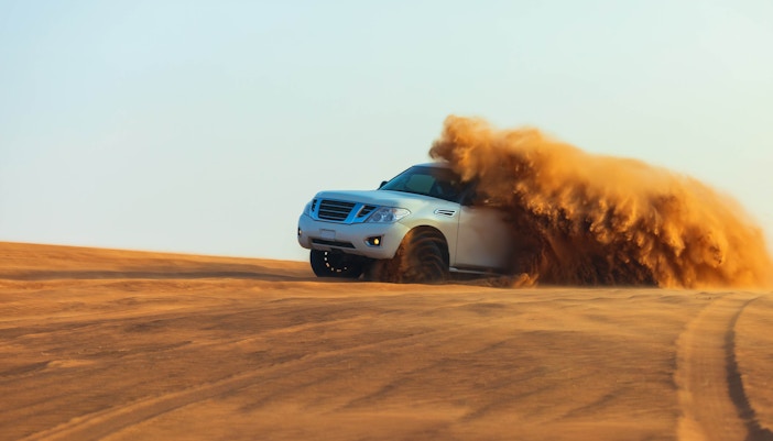 SUV driving through sand dunes on a Dubai desert safari.