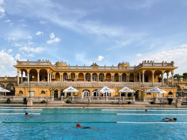 Szechenyi Baths Budapest thermal pools with people relaxing and enjoying the historic architecture.