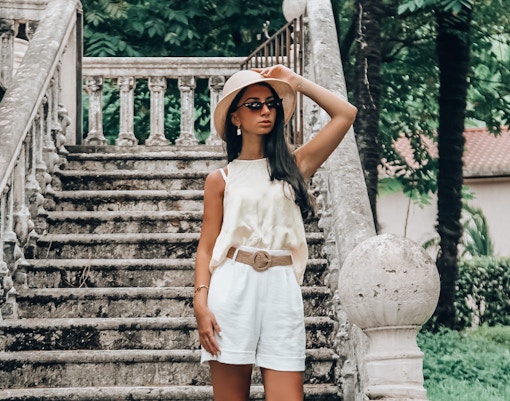 Person in summer attire on stone steps in Barcelona garden.