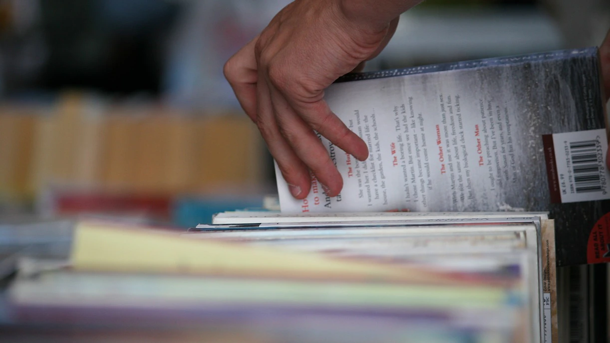 Hand selecting a book from a shelf in a bookshop.