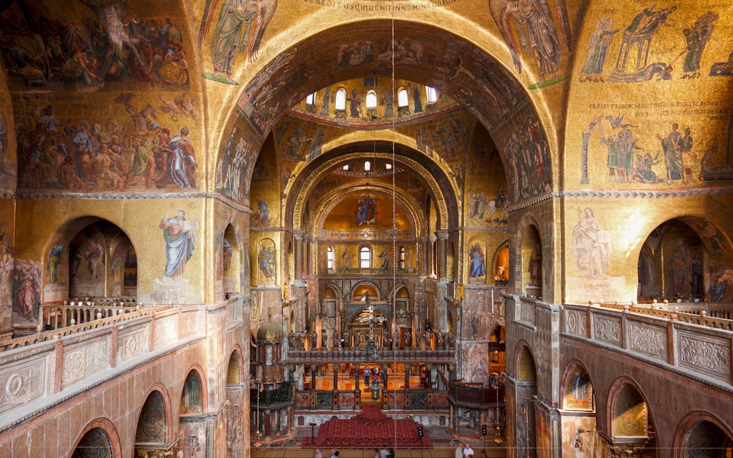 Interior view of St. Mark's Basilica with ornate golden mosaics and arches, Venice.