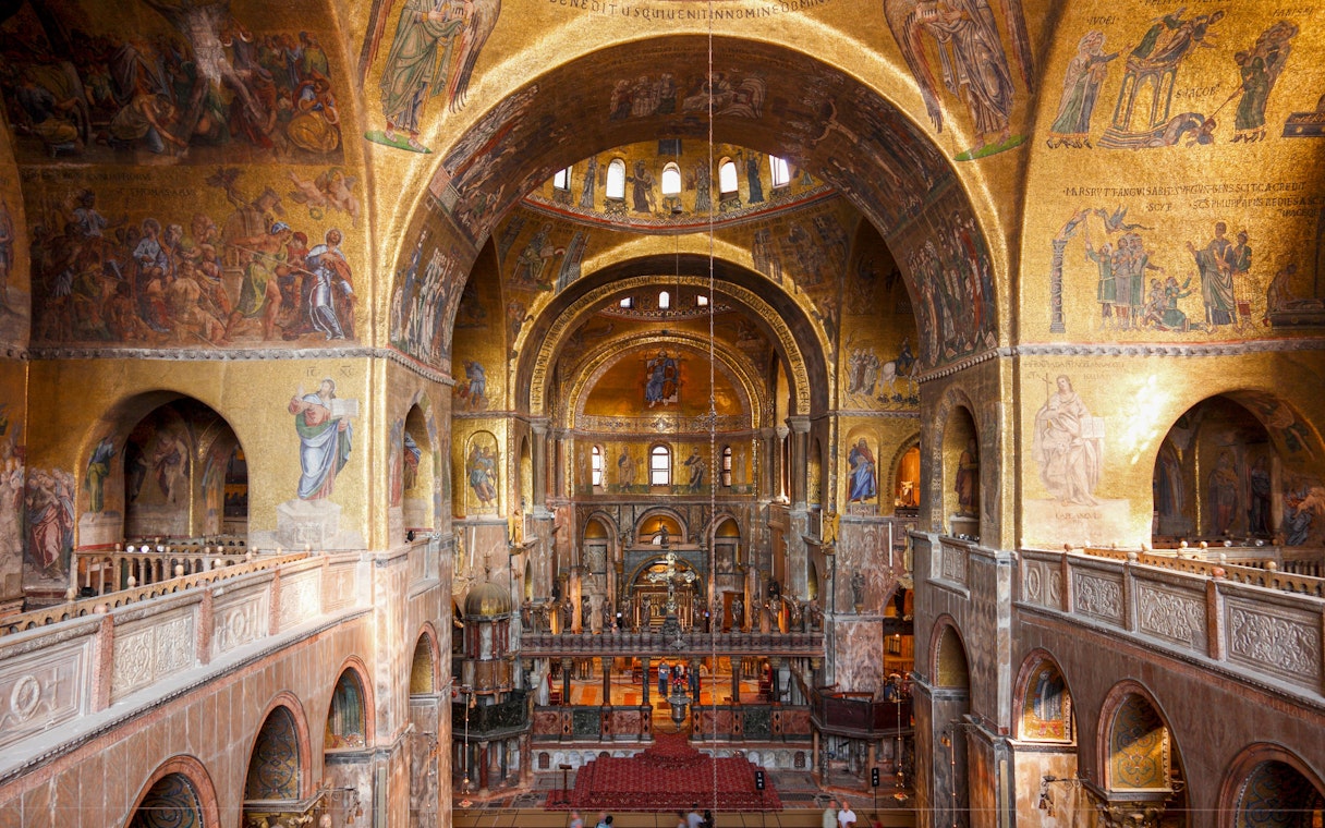 Interior view of St. Mark's Basilica with ornate golden mosaics and arches, Venice.