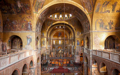 Interior view of St. Mark's Basilica with ornate golden mosaics and arches, Venice.