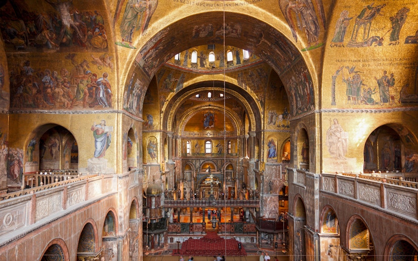 Interior view of St. Mark's Basilica with ornate golden mosaics and arches, Venice.