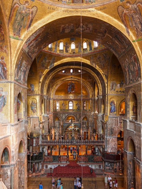 Interior view of St. Mark's Basilica with ornate golden mosaics and arches, Venice.
