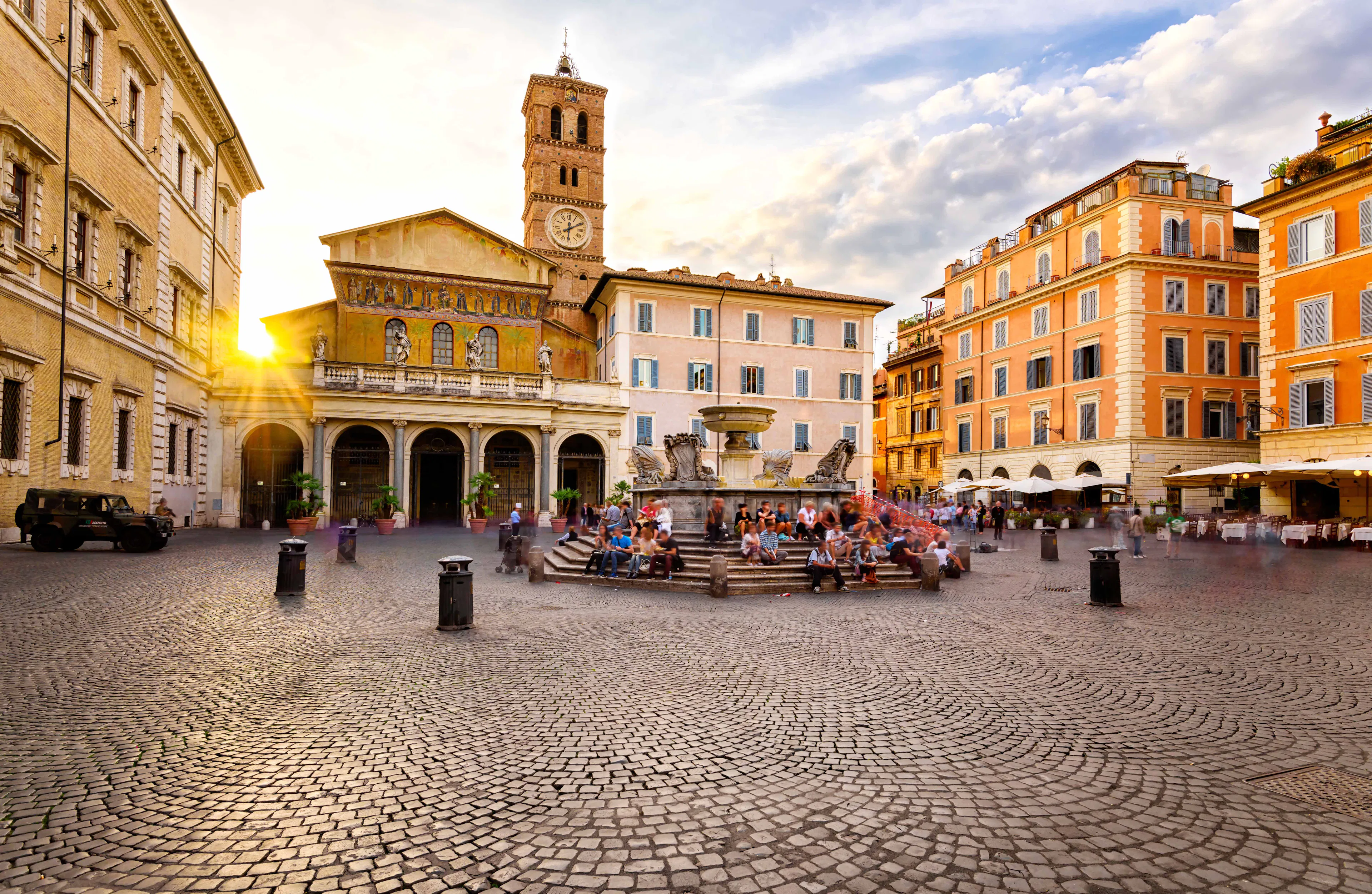 Basilica di Santa Maria in Trastevere with fountain and people in Rome's historic square.