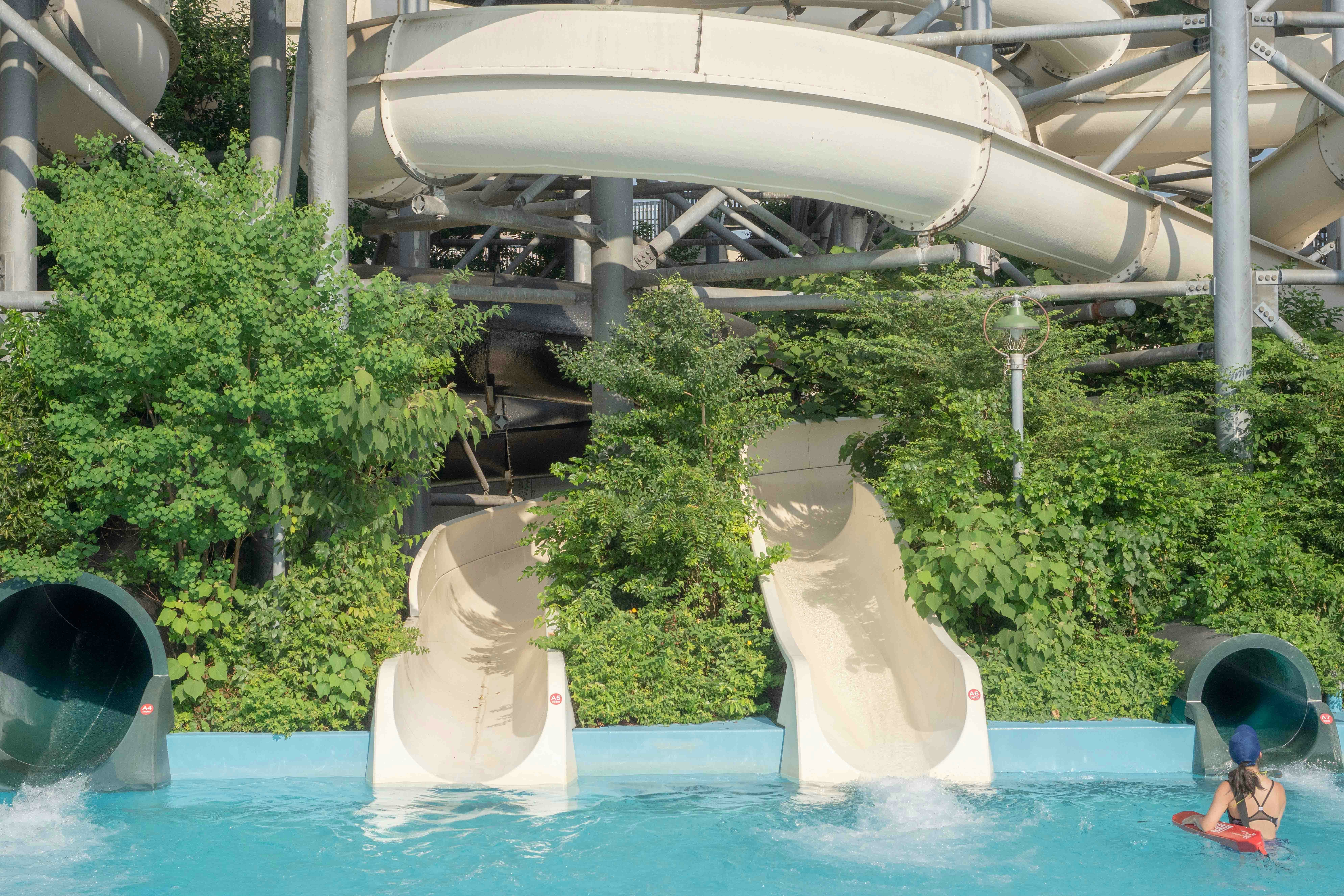 Water slides at Aquaboulevard Water Park in Paris with a swimmer in the pool.