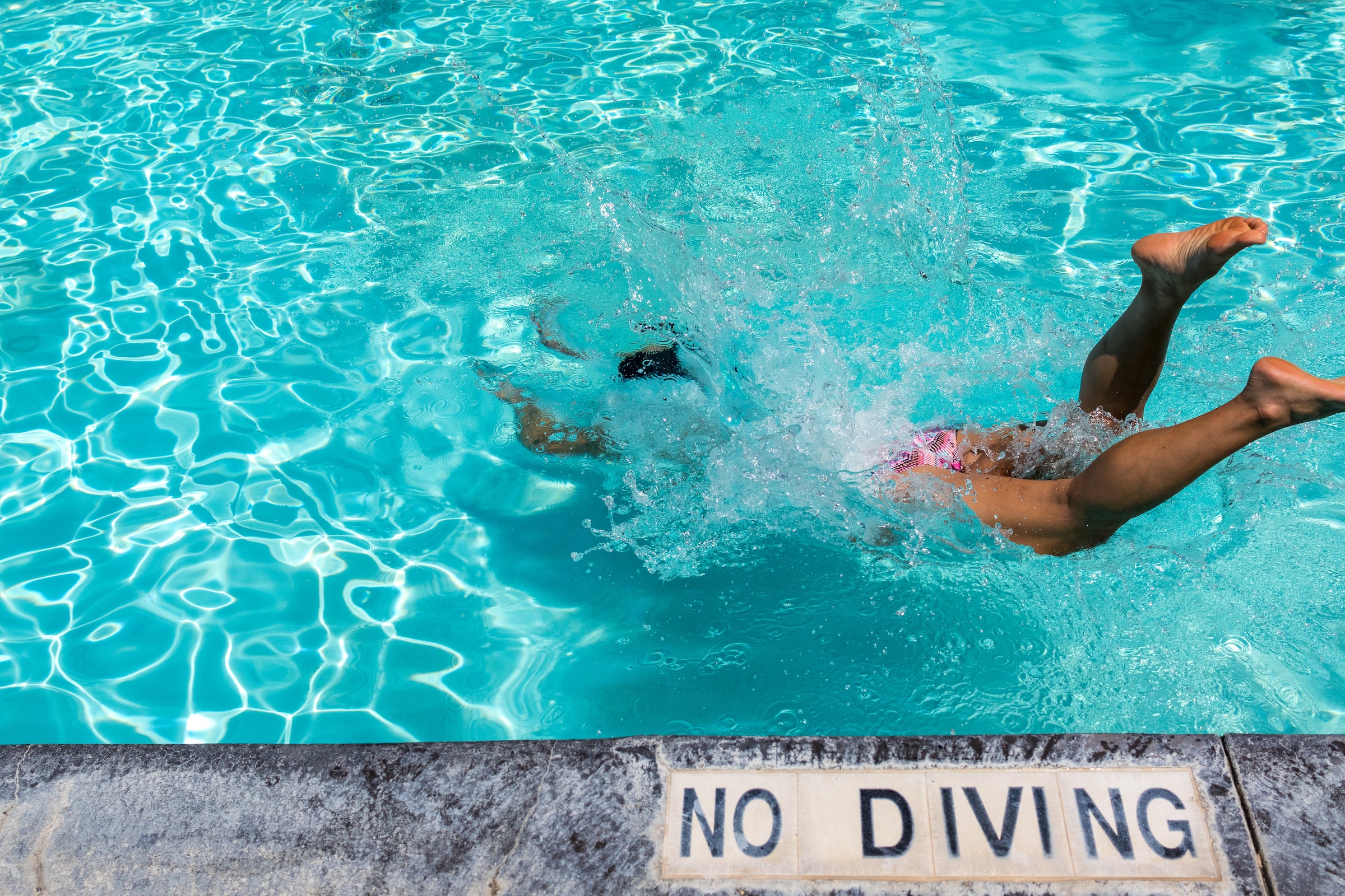 Person splashing into pool at Aquaventure Water Park with no diving sign.