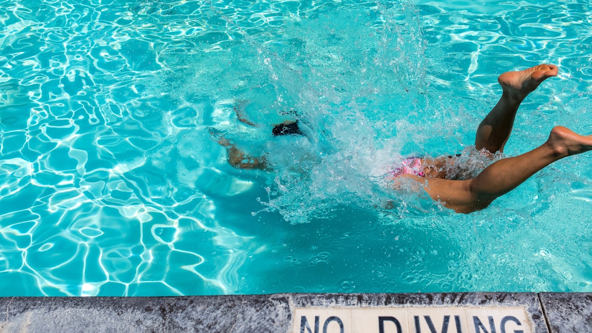 Person splashing into pool at Aquaventure Water Park with no diving sign.