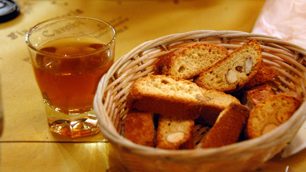 Cantucci biscuits in a basket with a glass of Vin Santo wine.