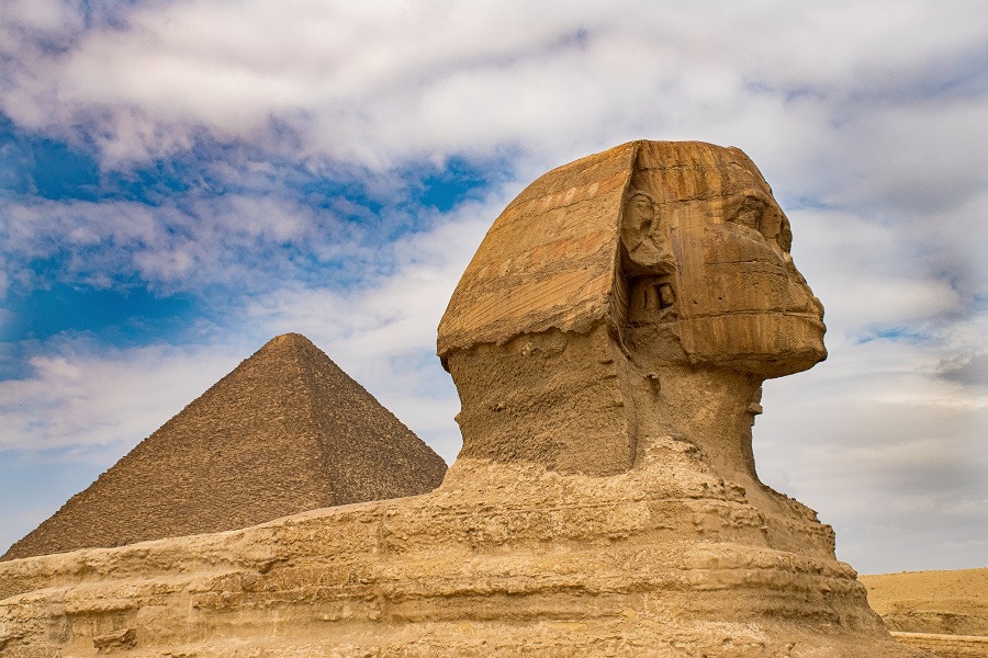 Sphinx and Pyramid of Giza under a cloudy sky in Egypt.
