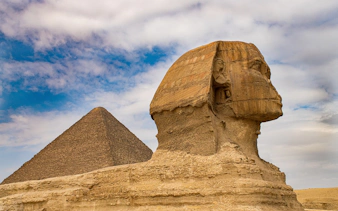 Sphinx and Pyramid of Giza under a cloudy sky in Egypt.