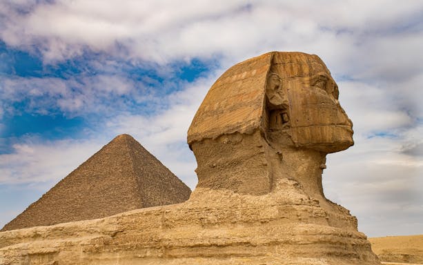 Sphinx and Pyramid of Giza under a cloudy sky in Egypt.