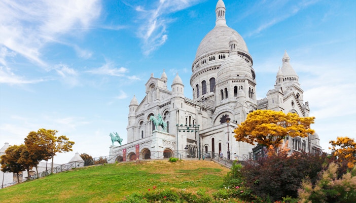 Sacré-Cœur Basilica on Montmartre Hill, Paris, viewed from a grassy slope.