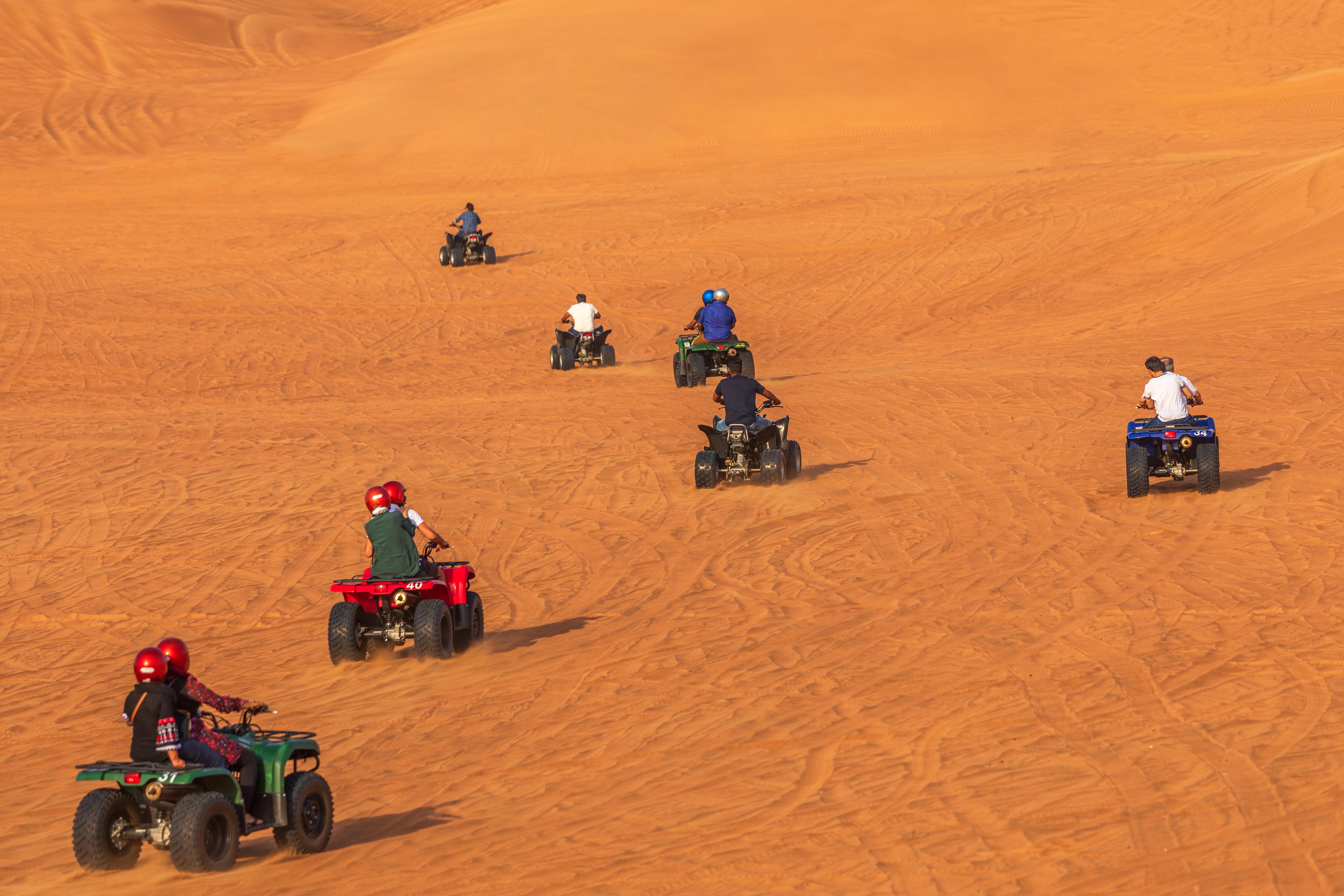 ATVs driving on sand dunes in Dubai desert.