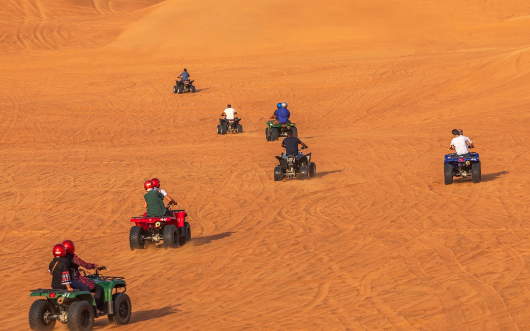 ATVs driving on sand dunes in Dubai desert.