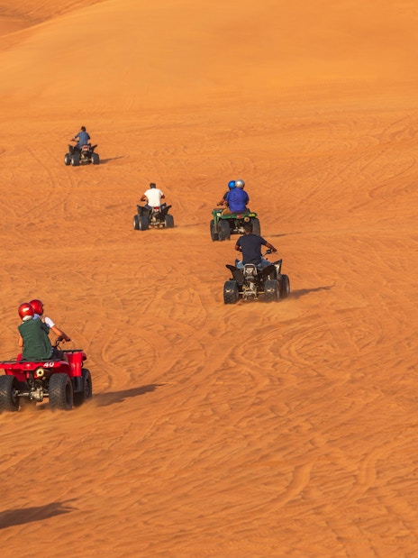 ATVs driving on sand dunes in Dubai desert.