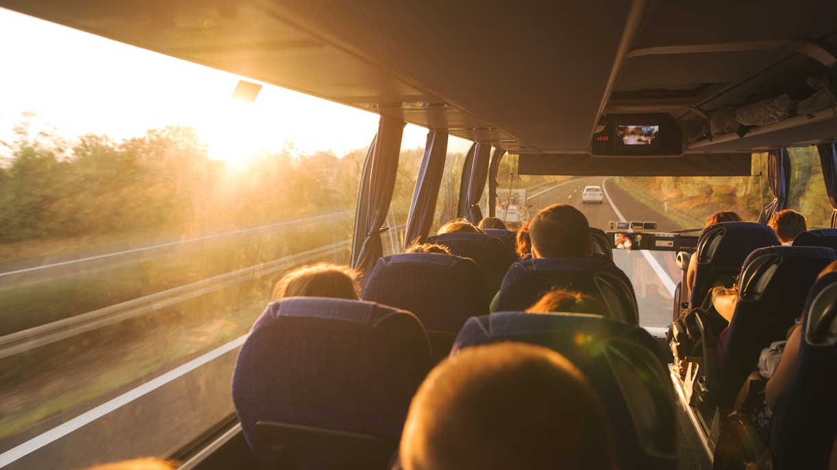 Bus interior with passengers traveling towards Phillip Island Nature Parks at sunset.
