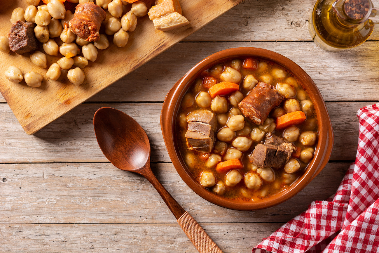 Cocido madrileño with chickpeas, meat, and vegetables in a clay bowl, Madrid cuisine.