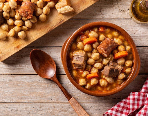 Cocido madrileño with chickpeas, meat, and vegetables in a clay bowl, Madrid cuisine.