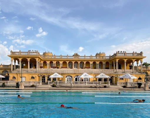 Thermal pools at Budapest's historic Széchenyi Baths with people enjoying the warm waters.