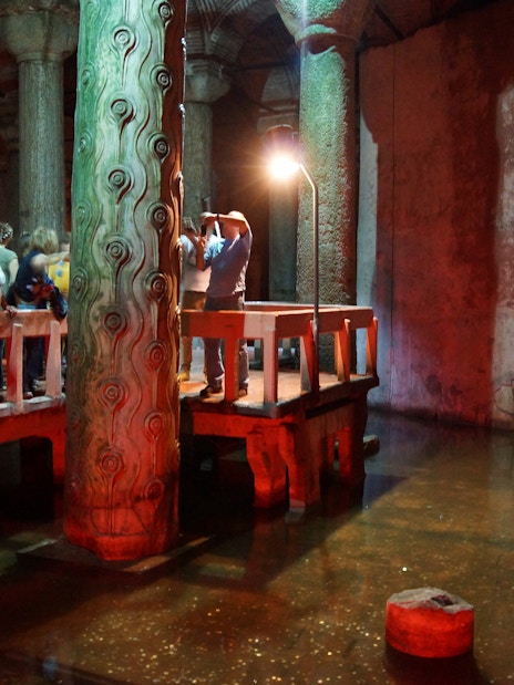 Visitors exploring the Basilica Cistern in Istanbul, viewing ancient columns and reflections in water.