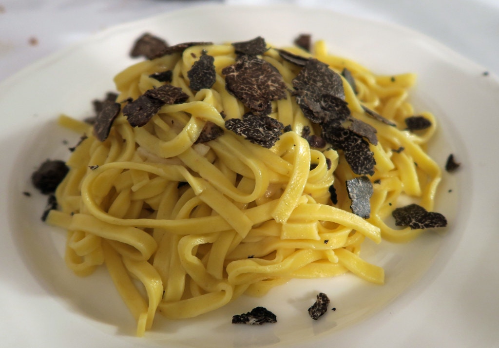 Tagliatelle with porcini mushrooms and truffle in an Italian restaurant setting.