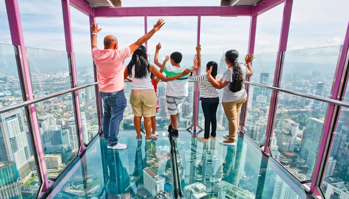 Visitors standing on the glass floor of KL Tower Sky Box, overlooking Kuala Lumpur cityscape.
