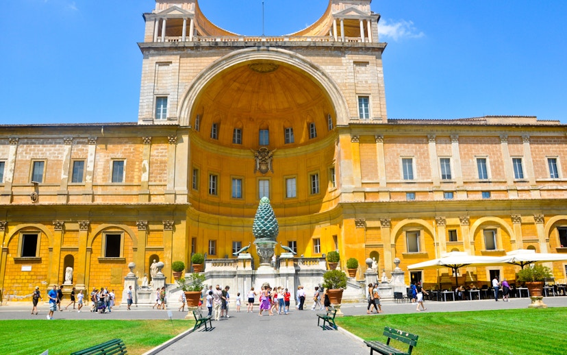 Vatican Museum courtyard with tourists in Rome, featuring the Pinecone sculpture.