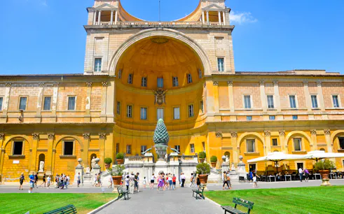 Vatican Museum courtyard with tourists in Rome, featuring the Pinecone sculpture.