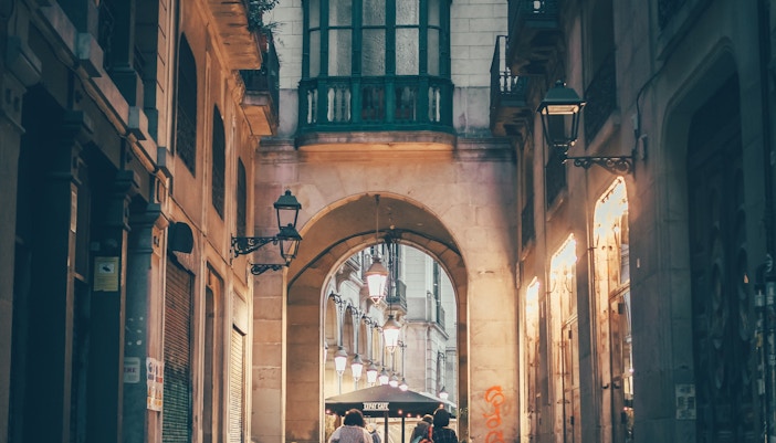 Narrow street in Gothic Quarter, Barcelona, with historic stone buildings and archways.
