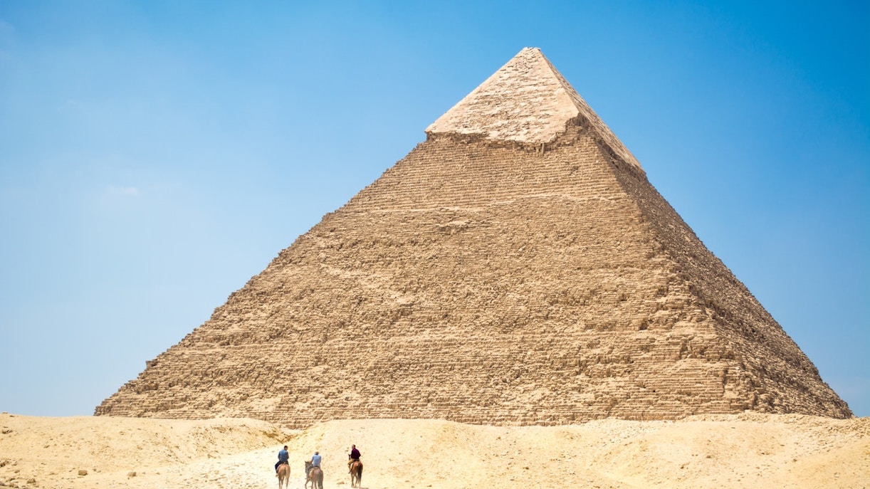 Khafre Pyramid at Giza with three people on camels in the foreground.