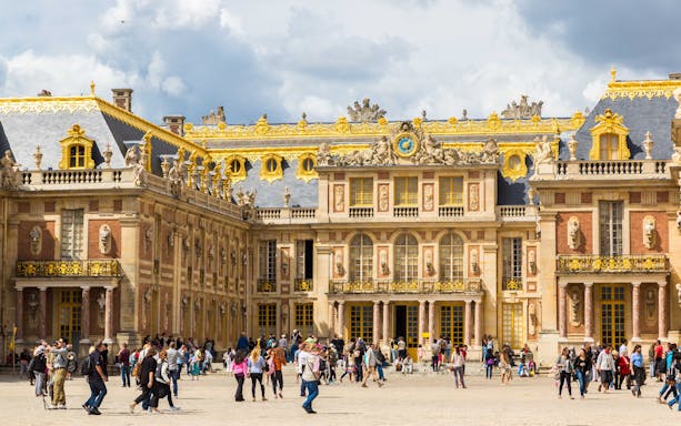 Visitors exploring the courtyard of the Palace of Versailles, France.