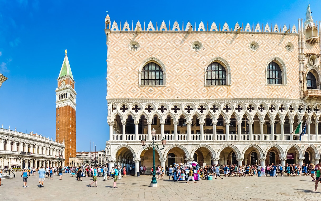Doge's Palace facade with tourists in Venice, Italy, near St. Mark's Campanile.