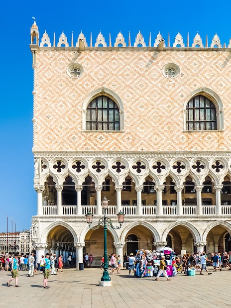 Doge's Palace facade with tourists in Venice, Italy, near St. Mark's Campanile.