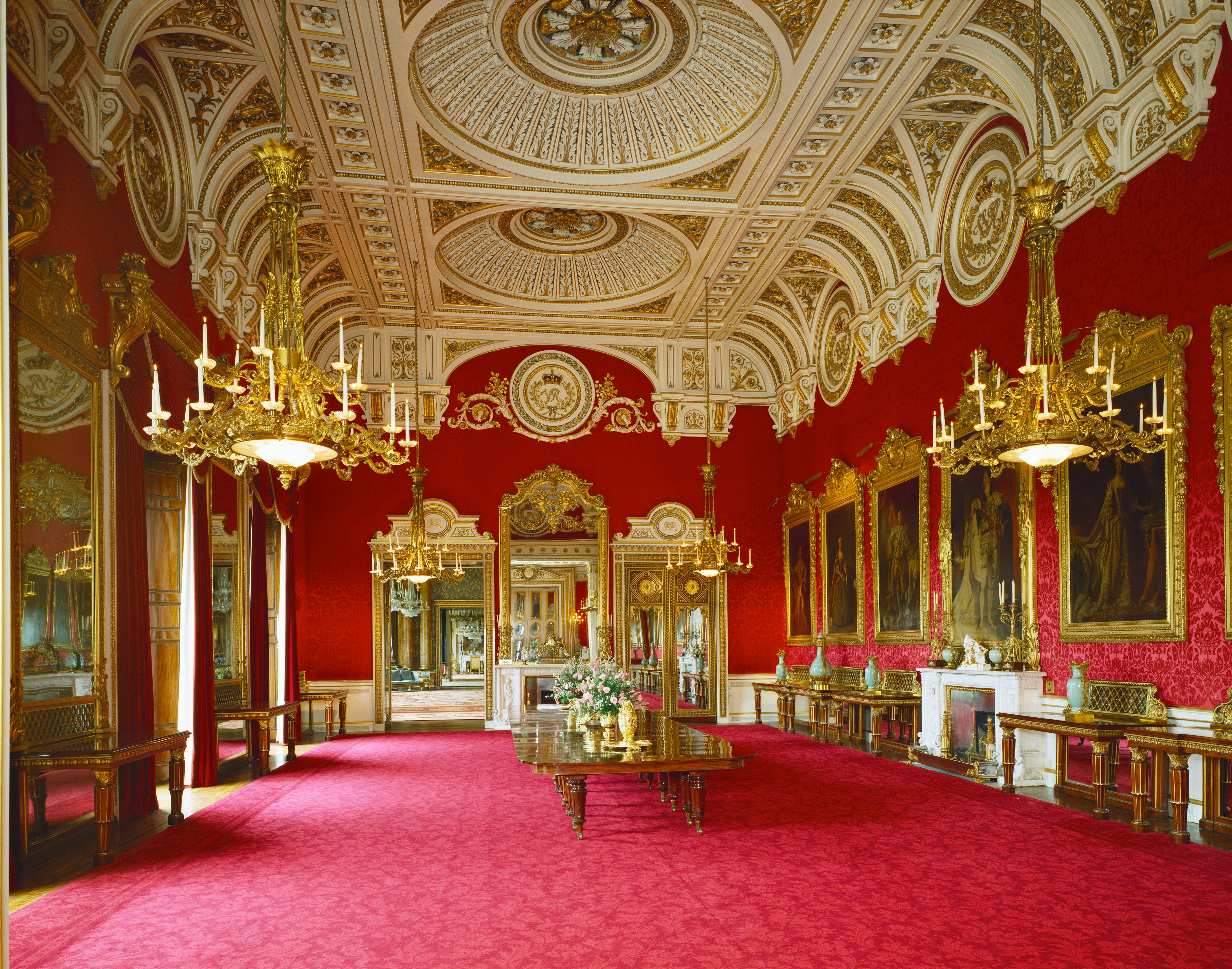 Buckingham Palace interior with ornate chandeliers and red decor.