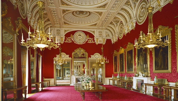 Buckingham Palace interior with ornate chandeliers and red decor.