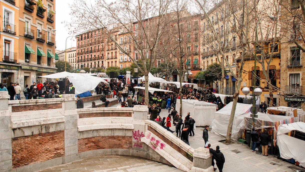 La Latina market scene in Madrid with people browsing stalls.