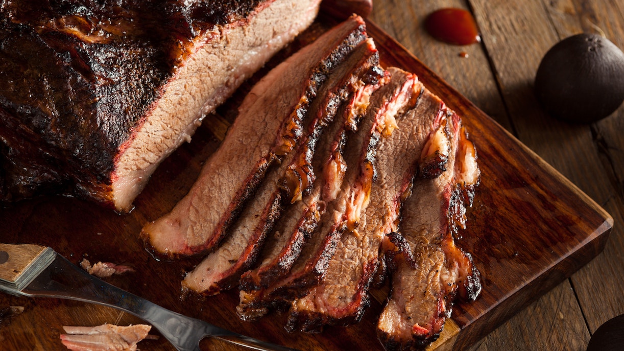 Sliced smoked brisket on a wooden board at London street food market Smokoloko.