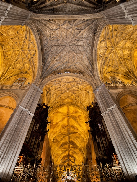 Seville Cathedral interior with ornate Gothic ceiling and columns.